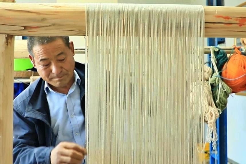 Ông Dương Vĩnh Lương bên khung dệt thảm, tại tỉnh Thanh Hải. Ảnh: Xinhua.