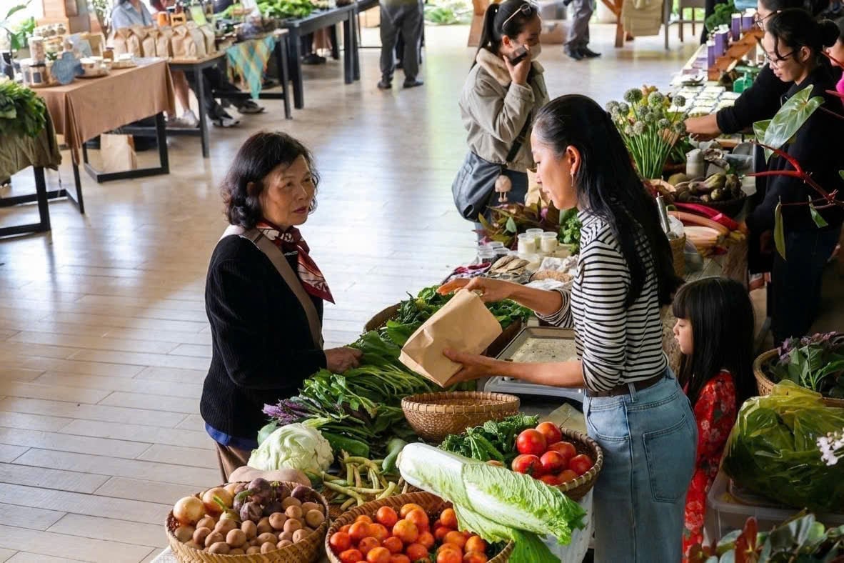 Khách hàng chọn mua rau, củ tại gian hàng ở Phiên chợ nông sản hữu cơ Đà Lạt, nơi nhịp mua bán diễn ra chậm rãi nhưng ổn định qua từng kỳ chợ. Ảnh: Nhật Tiến.